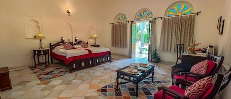 A room with a bed, a sofa, a coffee table, and a chandelier.