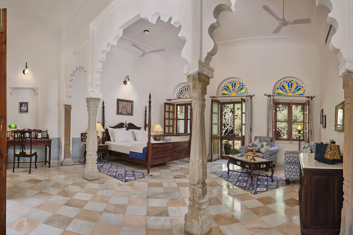A traditional room with a checkered floor, a bed, a desk, and a sofa.