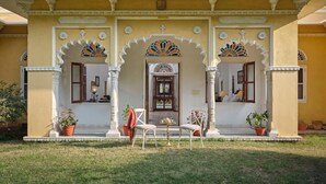 A traditional building with a yellow facade, ornate arches, and a balcony with railings. - Dev Shree Deogarh (Devgarh)
