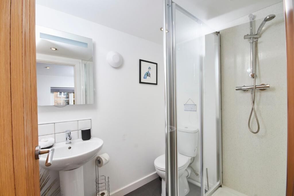 A modern bathroom with a glass shower enclosure, a white sink, and a toilet.