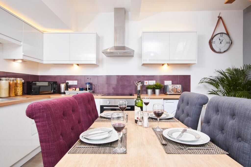 A modern kitchen with white cabinets, a central island, and a dining area with a table set for two.