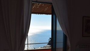 Une pièce avec vue sur la mer, visible à travers une fenêtre ornée de rideaux.
