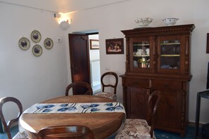 A dining area with a wooden table and chairs, a cabinet with glass doors, and wall-mounted plates. - La Fiorita: an oasis of tranquility between the sky and the sea in Positano (Positano)