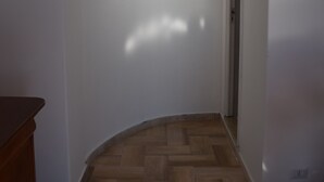 Une pièce avec un plancher en bois, des murs blancs et un meuble en bois.