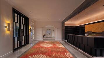 Vestíbulo de hotel con alfombra estampada, un mostrador de recepción y vistas del área del vestíbulo.