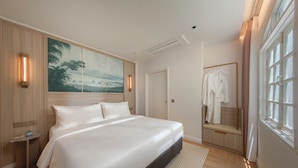 Habitación de hotel con una cama grande, un cuadro en la pared, un espejo y una ventana.