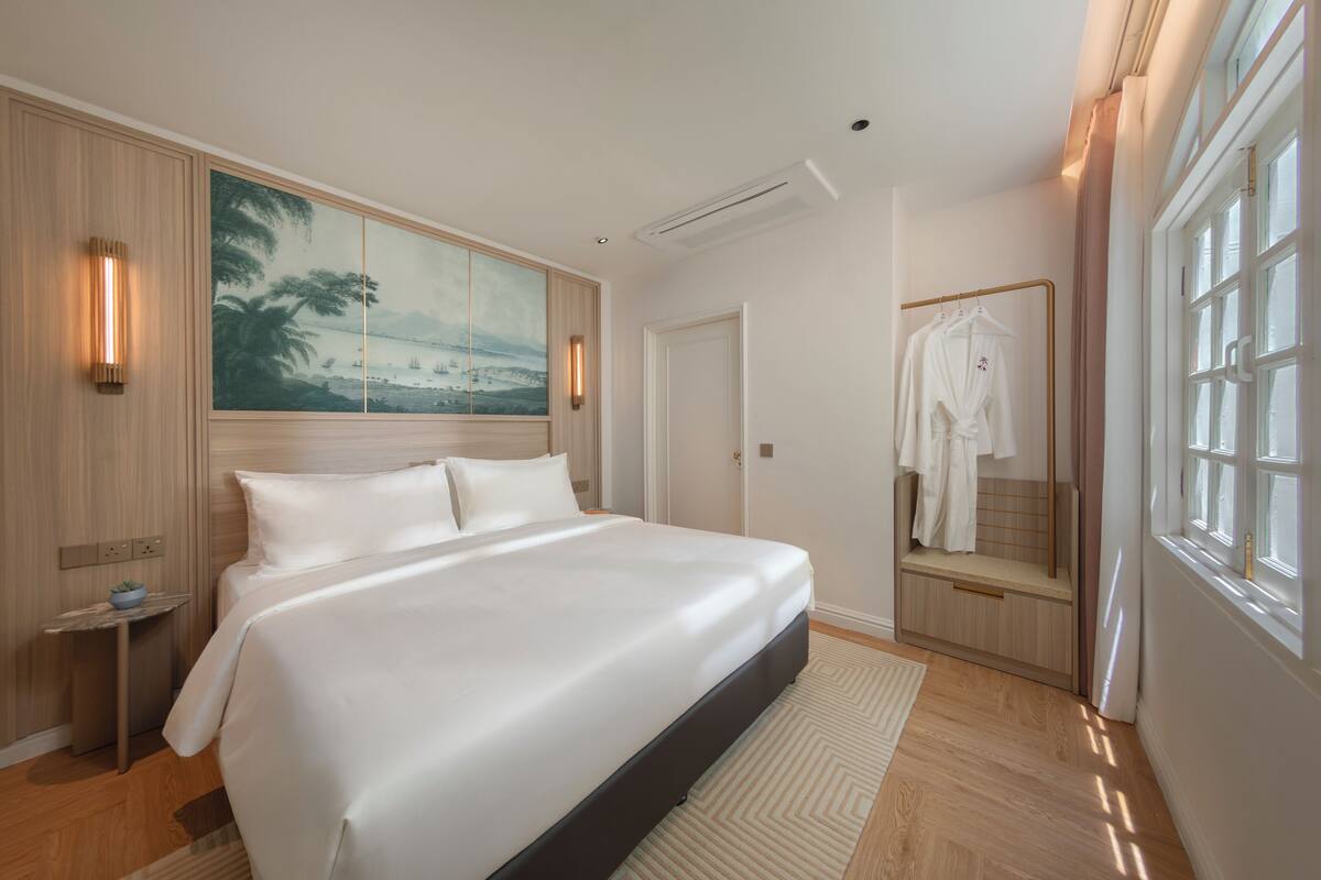 Habitación de hotel con una cama grande, un cuadro en la pared, un espejo y una ventana.