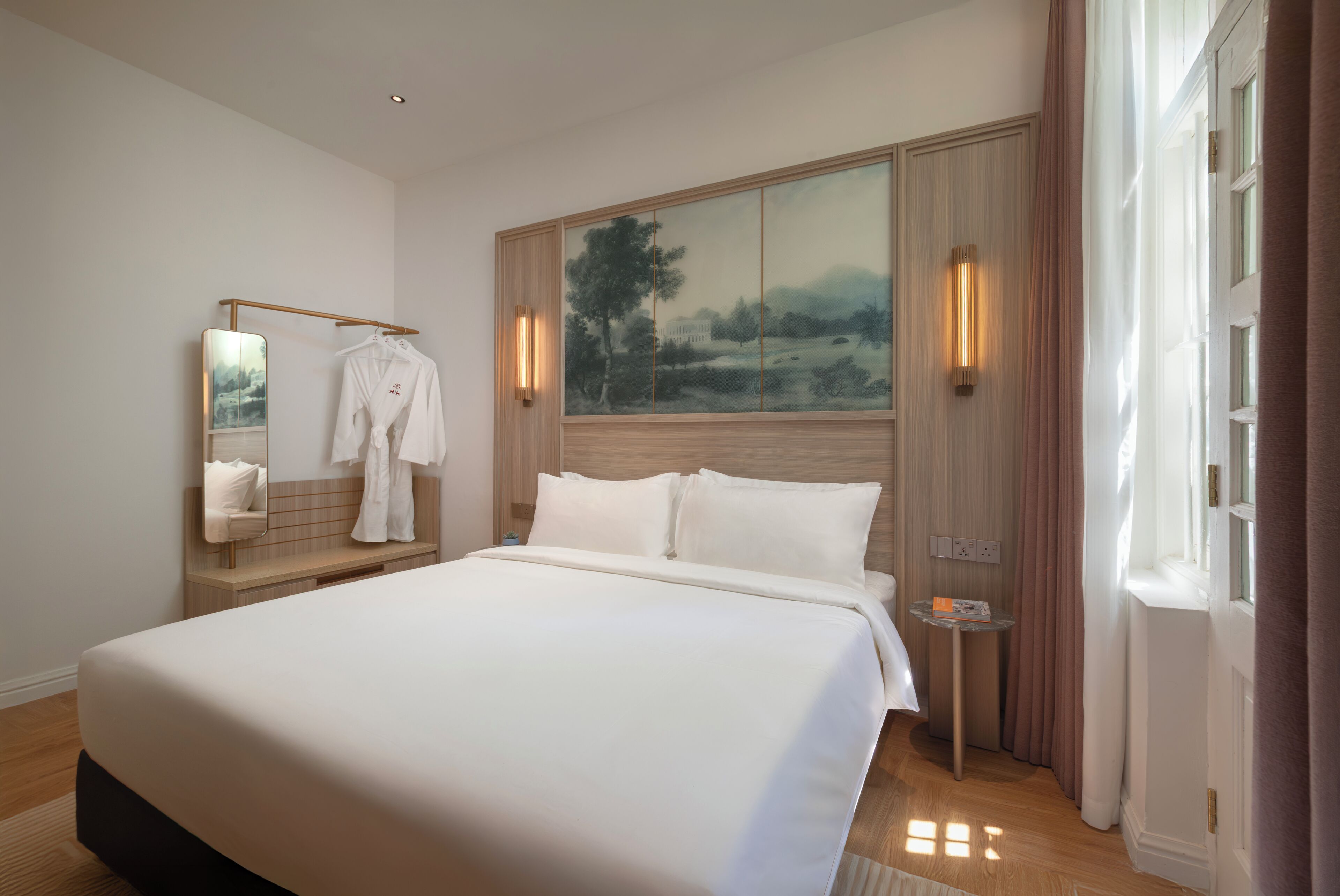 A bedroom with a large bed, a mirror, a painting, and a small table.