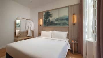 A bedroom with a large bed, a mirror, a painting, and a small table.