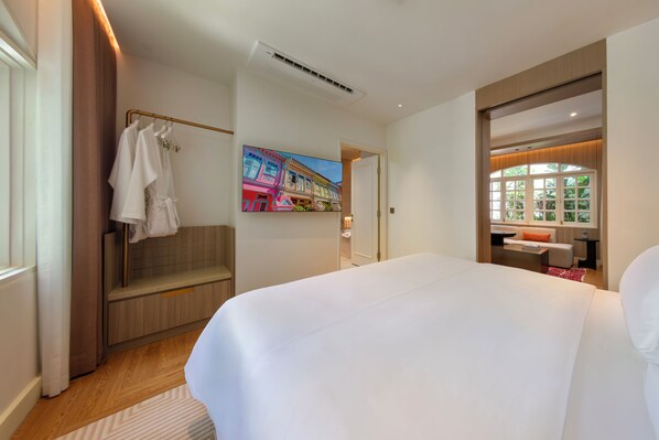 A hotel room with a large bed, a seating area with a view, a painting on the wall, and a bathroom visible through an open door.