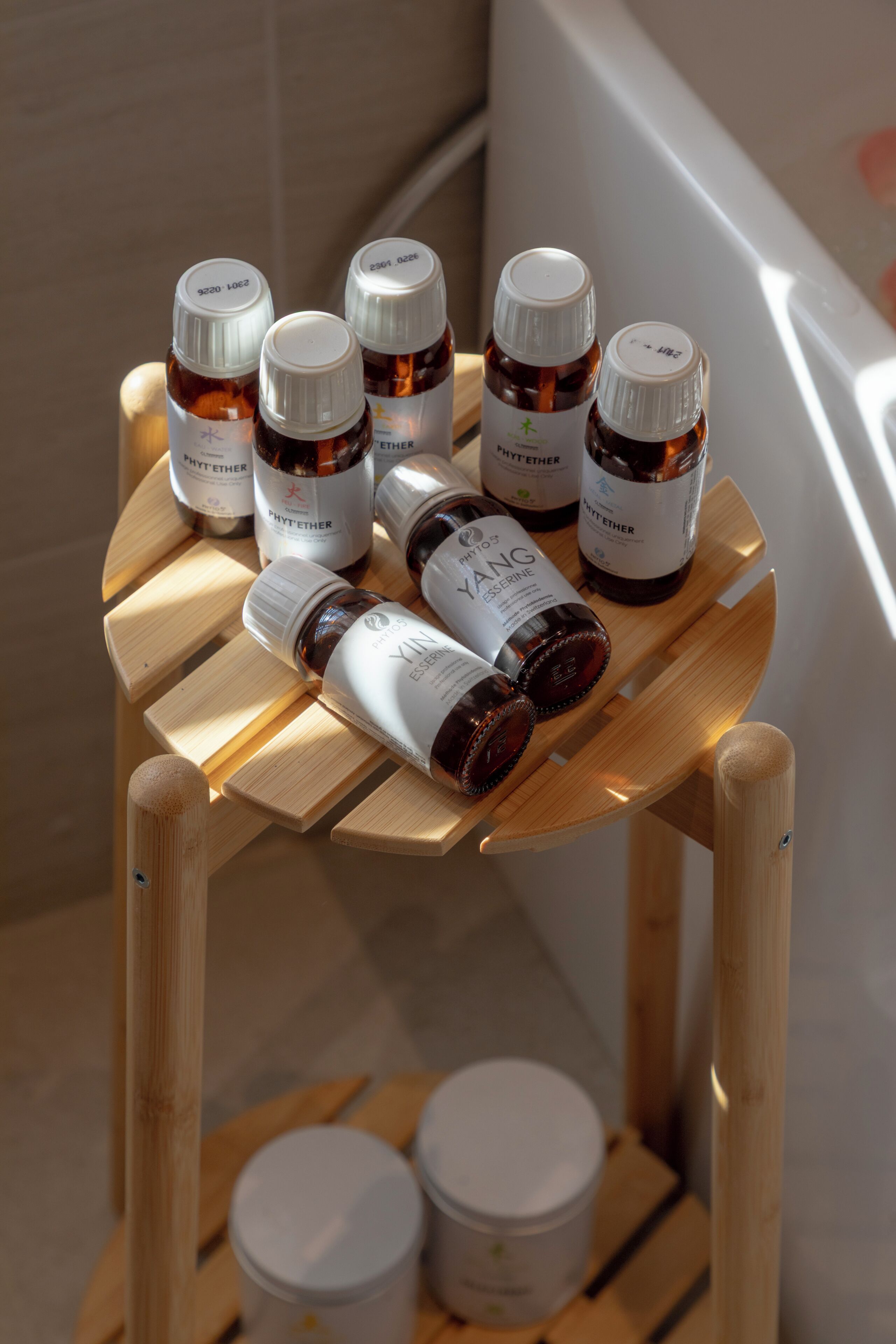 A wooden stool with bottles of essential oils and containers on it.