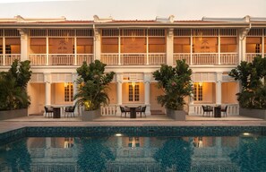 A hotel with a pool, outdoor seating, and a facade with the year 1926.