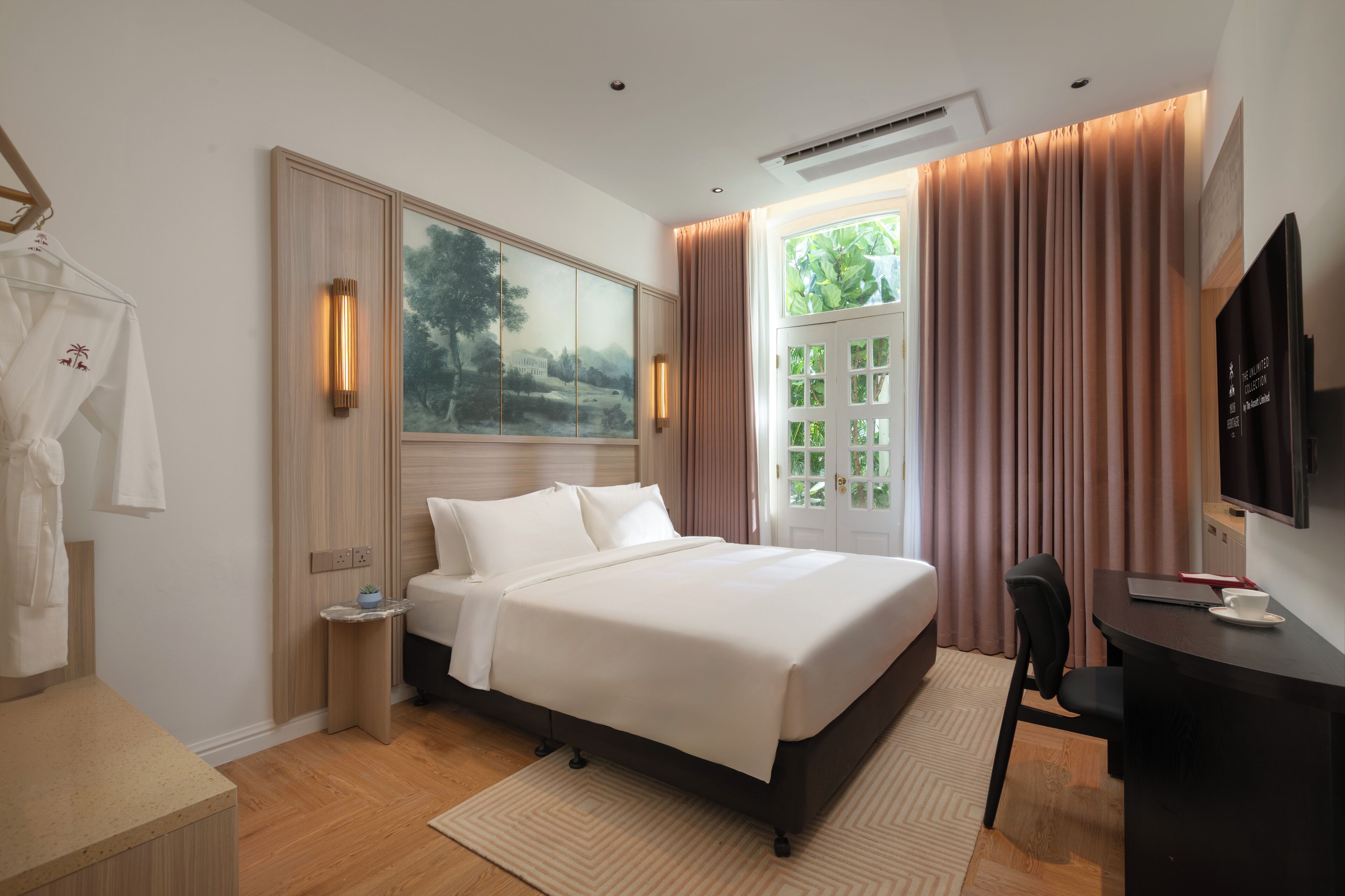 A hotel room with a bed, a desk, a chair, a TV, and a painting on the wall.