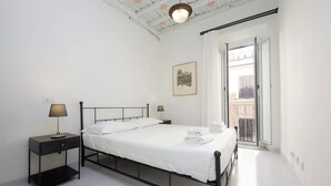 A minimalist bedroom with a bed, bedside tables, a ceiling light, and a view of the outside balcony. - Boschetto charming apartment in Monti (Roma)