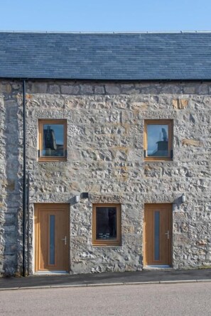 Un bâtiment en pierre doté de trois portes en bois et de deux fenêtres.