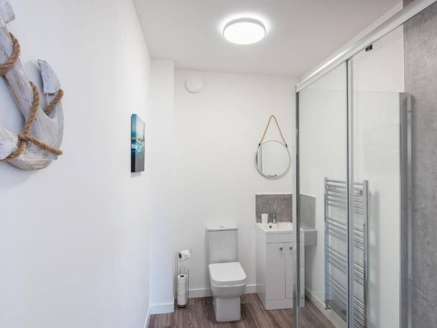 Uma casa de banho moderna com sanita, lavatório e cabine de duche em vidro.