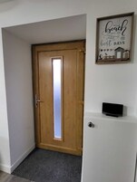 A wooden door with a frosted glass panel, a small television on a white stand, and a wall-mounted sign that reads "Beach days are the best days."