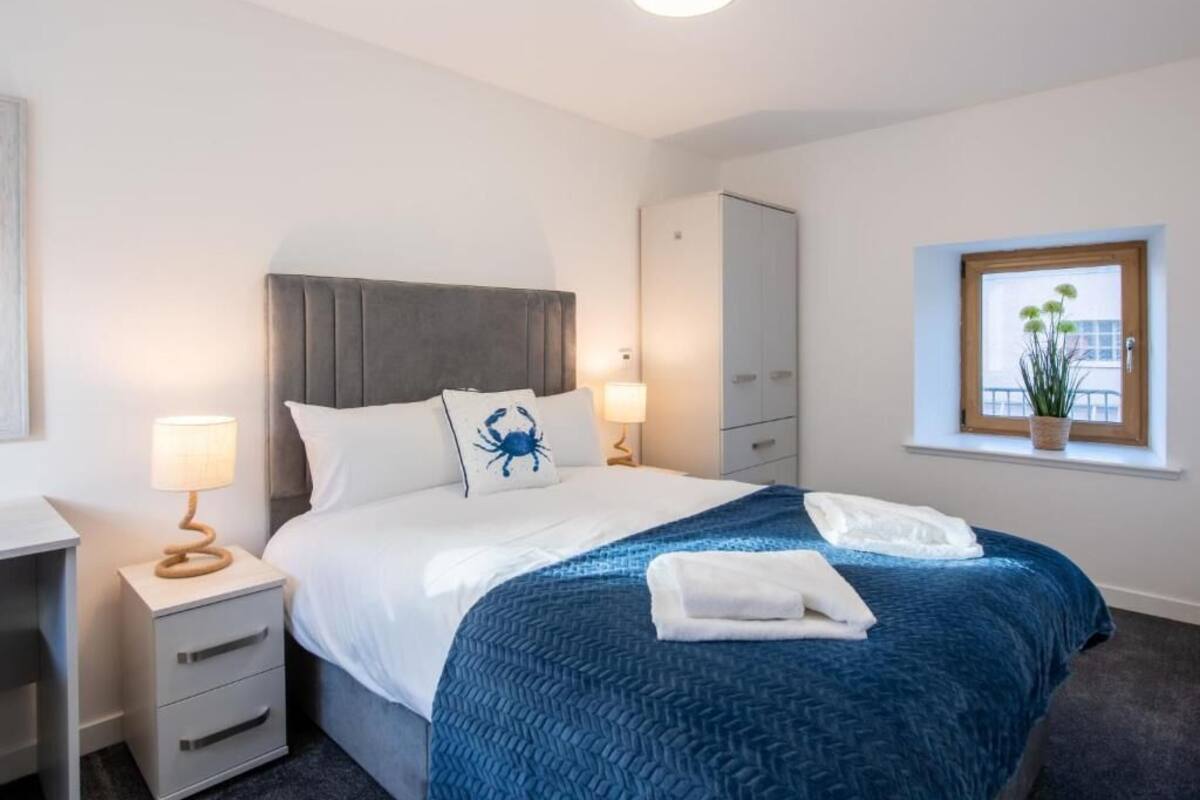 Habitación de hotel con cama, mesitas de noche, armario, ventana con vistas y luz de techo.