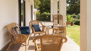 A covered outdoor seating area with wicker furniture and a view of the garden. - Ermal Green Haven (Vieira do Minho)