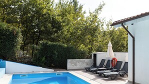 A swimming pool with lounge chairs and an umbrella, surrounded by greenery and a white building. - Ermal Green Haven (Vieira do Minho)