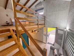 A loft-style room with a wooden staircase, a built-in bench, and a view of the outside. - Air-conditioned bungalow in southern Martinique (Rivière-Salée)