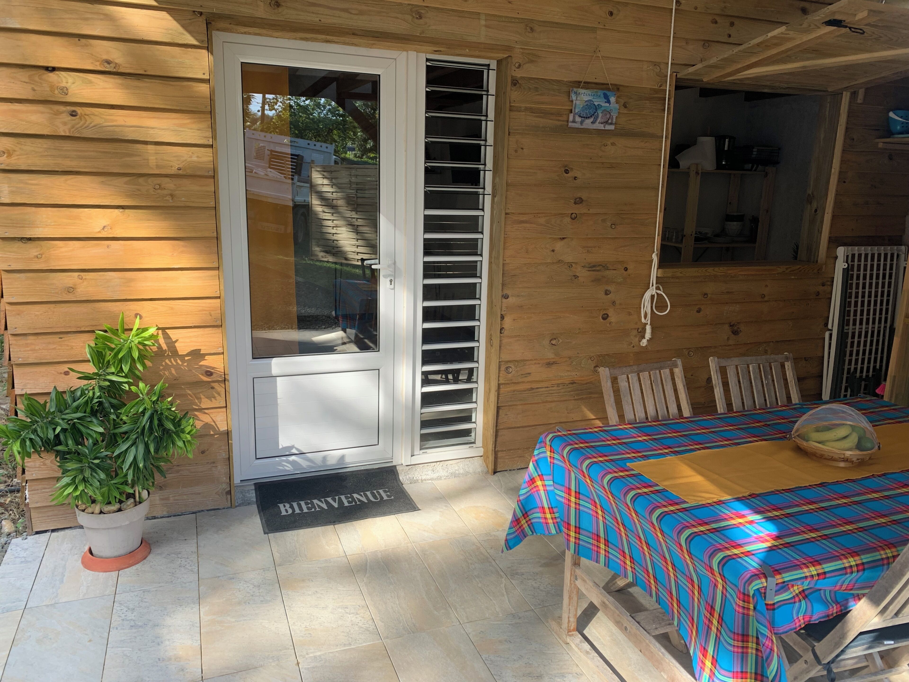 A wooden cabin with a sliding door, a dining table with a plaid tablecloth, and a potted plant.