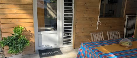 A wooden cabin with a sliding door, a dining table with a plaid tablecloth, and a potted plant.
