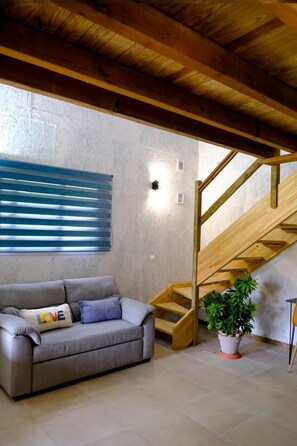 A room with a grey sofa, a wooden staircase, and a potted plant. - Air-conditioned bungalow in southern Martinique (Rivière-Salée)