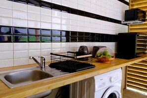 A kitchen with a stainless steel sink, a black drying rack, a toaster, and a basket of fruit on the countertop. - Air-conditioned bungalow in southern Martinique (Rivière-Salée)