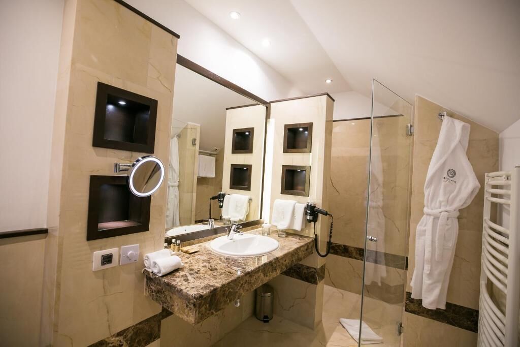 Une salle de bain moderne avec un lavabo en marbre, un grand miroir et une douche à parois de verre.