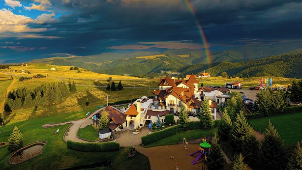 A rural village with houses, a playground, and a mountain backdrop.