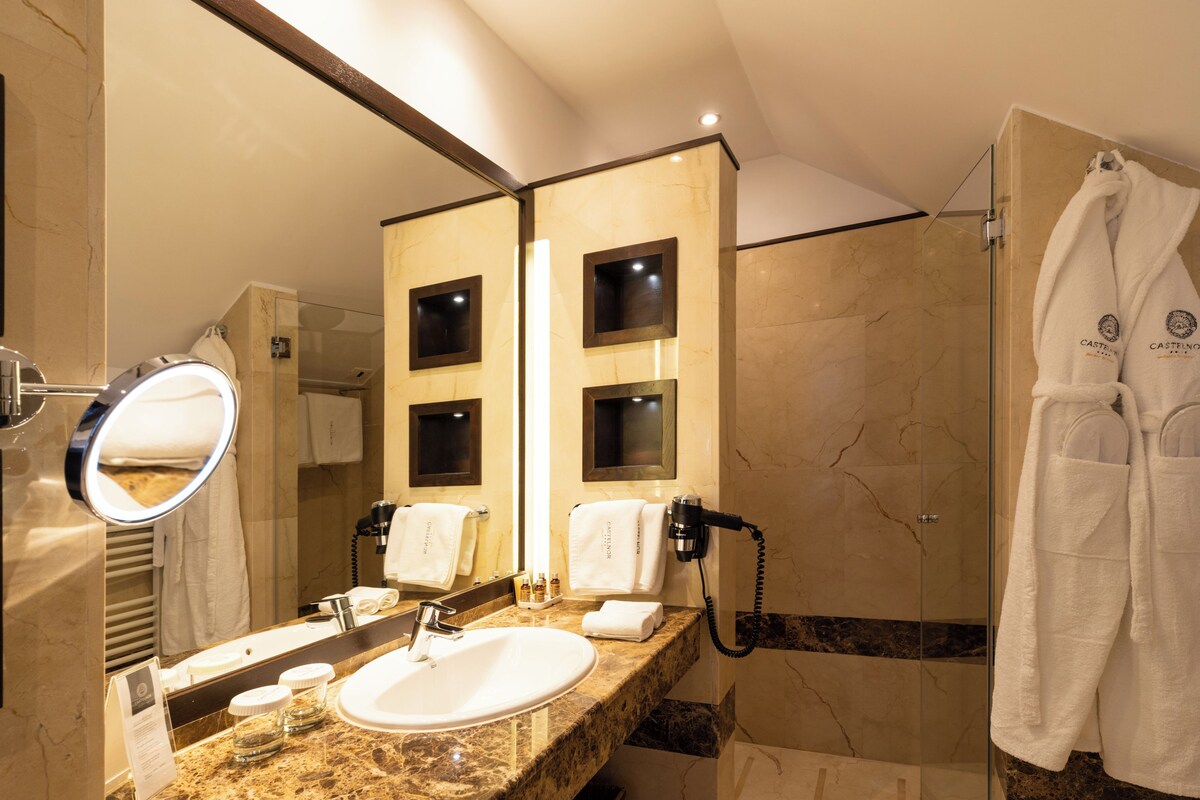 A bathroom with a sink, mirror, and a glass-enclosed shower area.