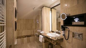 A modern bathroom with a glass shower, a marble sink, and a built-in hairdryer.