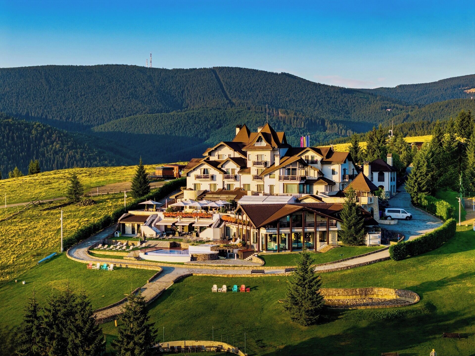 Un hotel grande con varias edificaciones, una piscina y vistas a colinas circundantes.