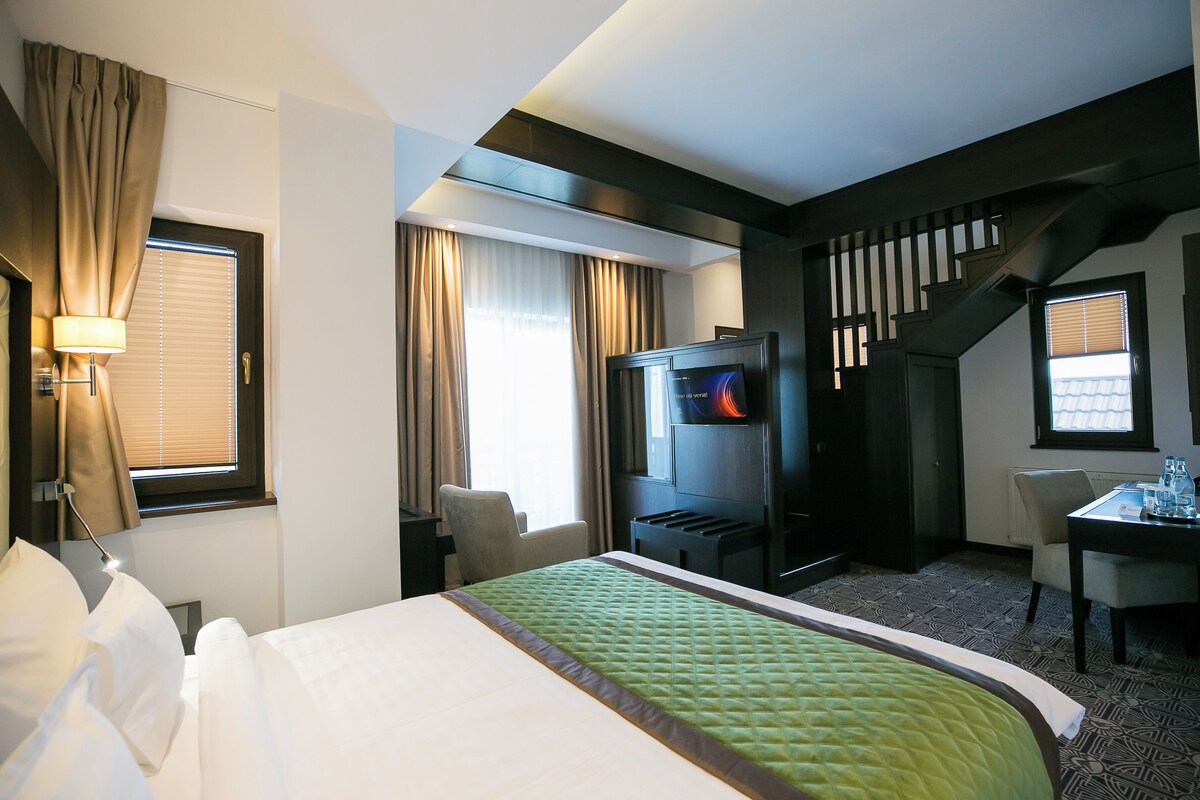 A hotel room with a bed, a TV, a desk, and a chair.