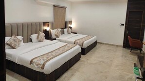 Habitación de hotel con dos camas, ventilador de techo, aire acondicionado y una puerta con panel oscuro.