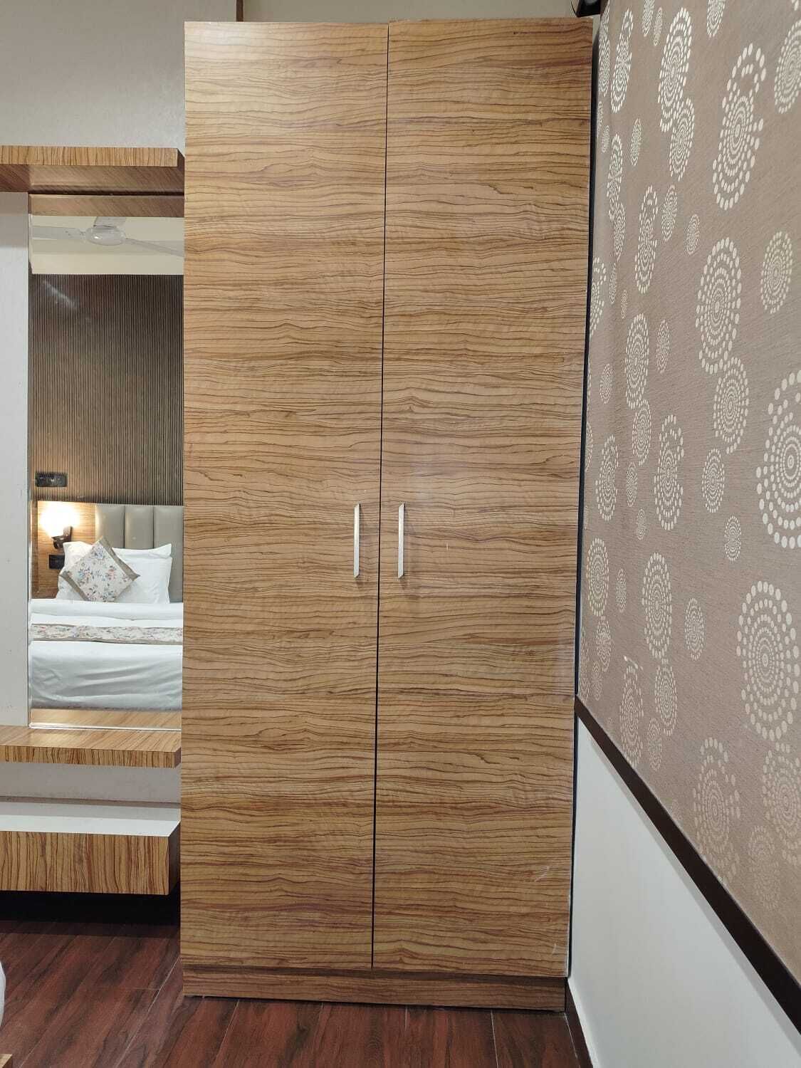 Ein Schlafzimmer mit einem Holzschrank, einem Bett mit weißer Bettwäsche und einer Wand mit Musterpapier.