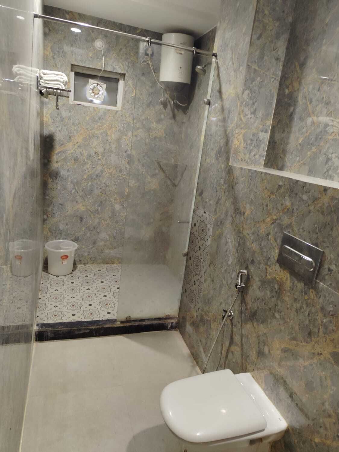 A modern bathroom with a glass-enclosed shower, a toilet, and a small sink area.