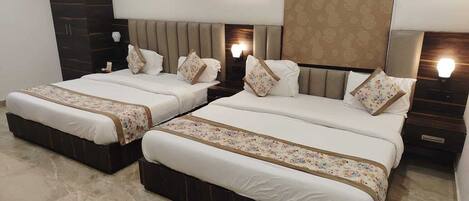 Habitación de hotel con dos camas, un armario de madera oscura, un espejo grande y un cabecero estampado.