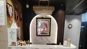 Una recepción con diseño de mármol, un candelabro, cuadros enmarcados y un reloj en la pared.