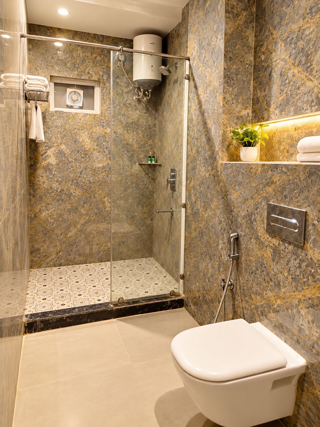 A modern bathroom with a glass-enclosed shower, a toilet, and marble walls.