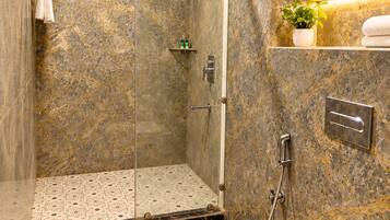 Een moderne badkamer met een douchecabine van glas, een toilet en marmeren wanden.
