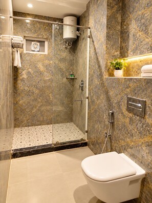 Une salle de bain moderne avec une douche à parois de verre, des toilettes et des murs en marbre.