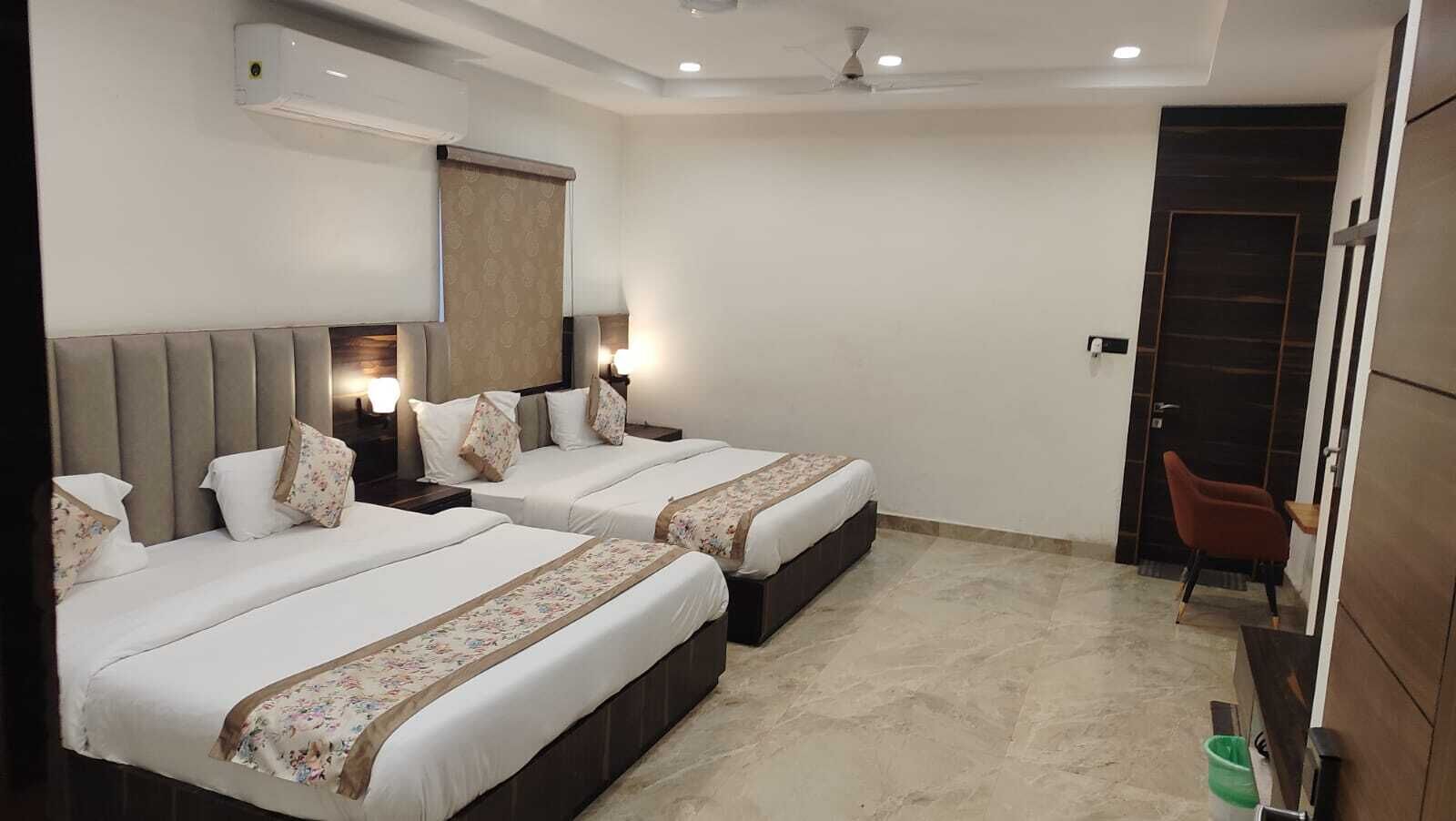 A hotel room with two beds, a desk, a chair, and a wardrobe.