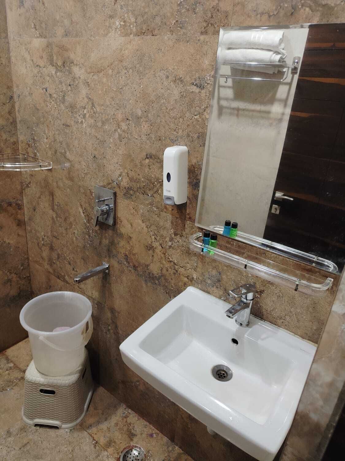 A bathroom with a white sink, a towel dispenser, a soap dispenser, and a hand dryer.