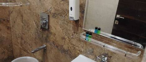 A bathroom with a white sink, a towel dispenser, a soap dispenser, and a hand dryer.