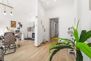 Ein modernes Wohnzimmer mit Essbereich, Küche und einem Flur, der in einen weiteren Raum führt.