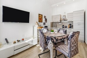 Eine moderne Küche mit weißen Schränken, einem Flachbildfernseher und einem Essbereich mit Tisch und Stühlen.