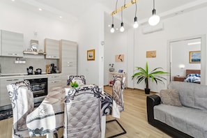 Eine moderne Küche mit eingebauten Geräten, ein Essbereich mit Tisch und Stühlen, eine Sitzecke und ein Blumentopf.