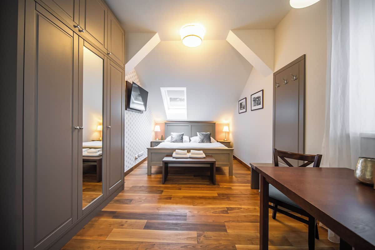 Un dormitorio con una cama grande, mesitas de noche, un banco y suelo de madera.